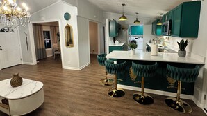 Una cocina moderna con armarios verdes, una isla de mármol y taburetes de bar.