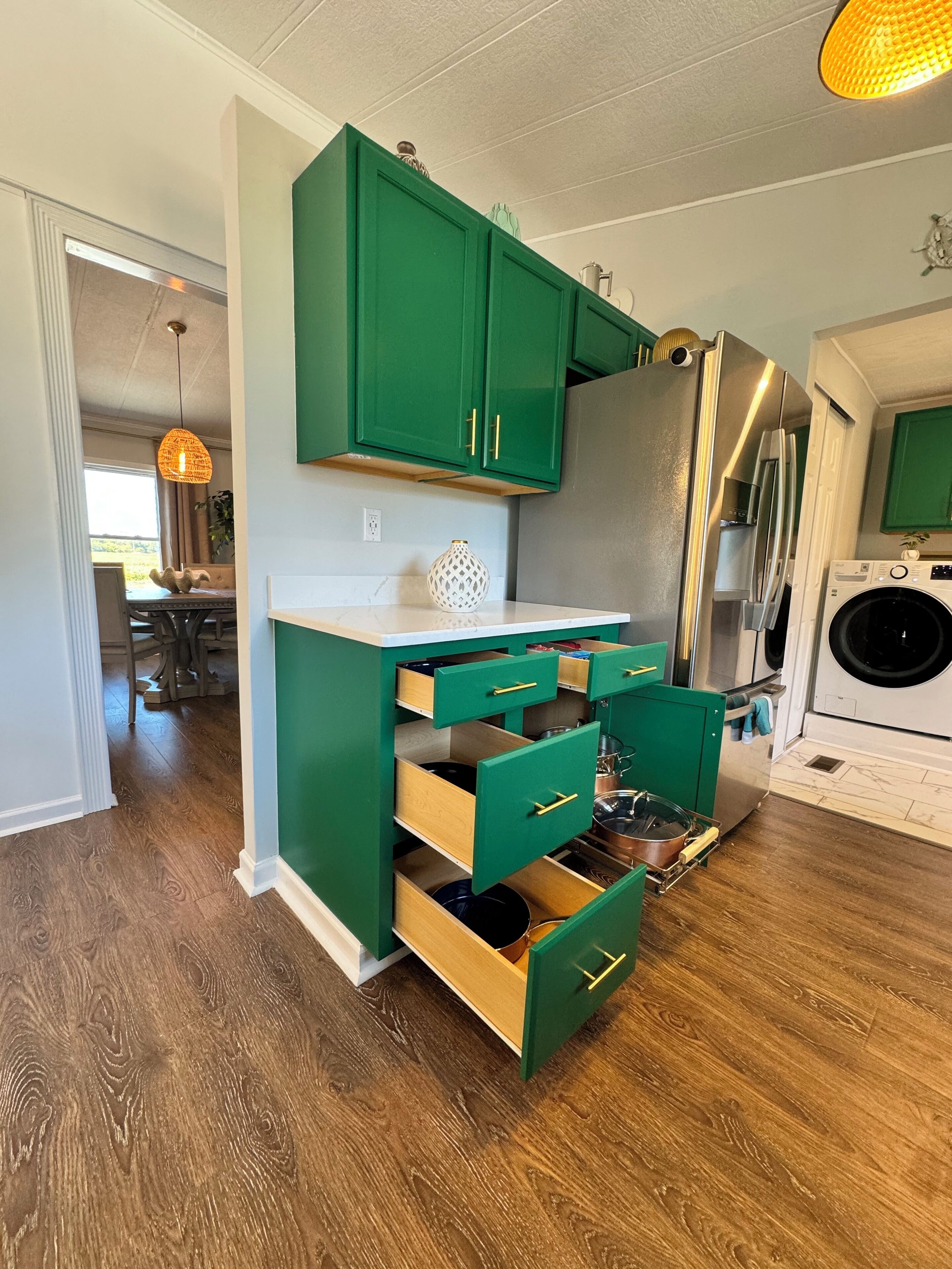 A kitchen with green cabinets, a stainless steel refrigerator, and a built-in washing machine.