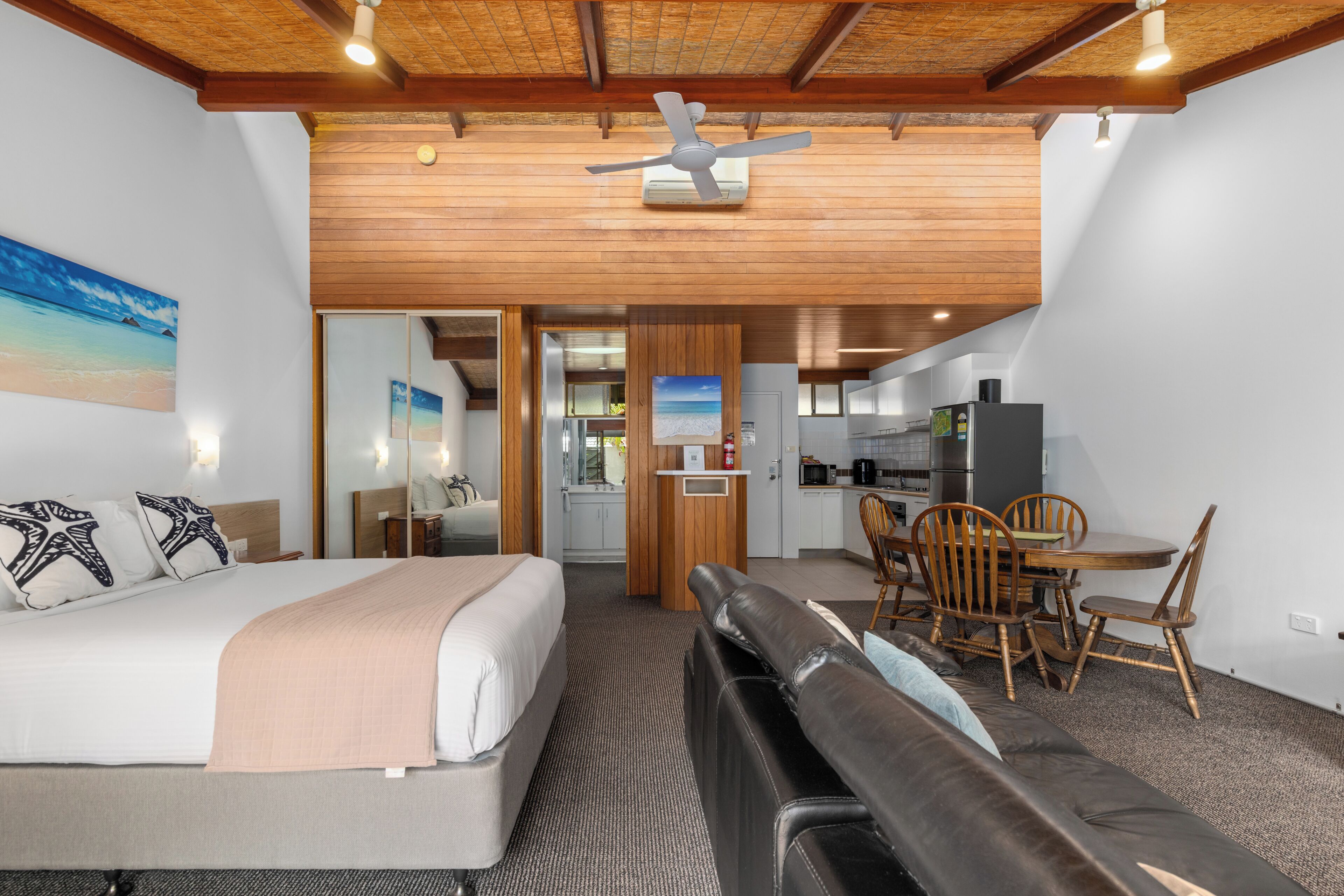 A hotel room with a bed, a seating area, a dining table, and a kitchenette.