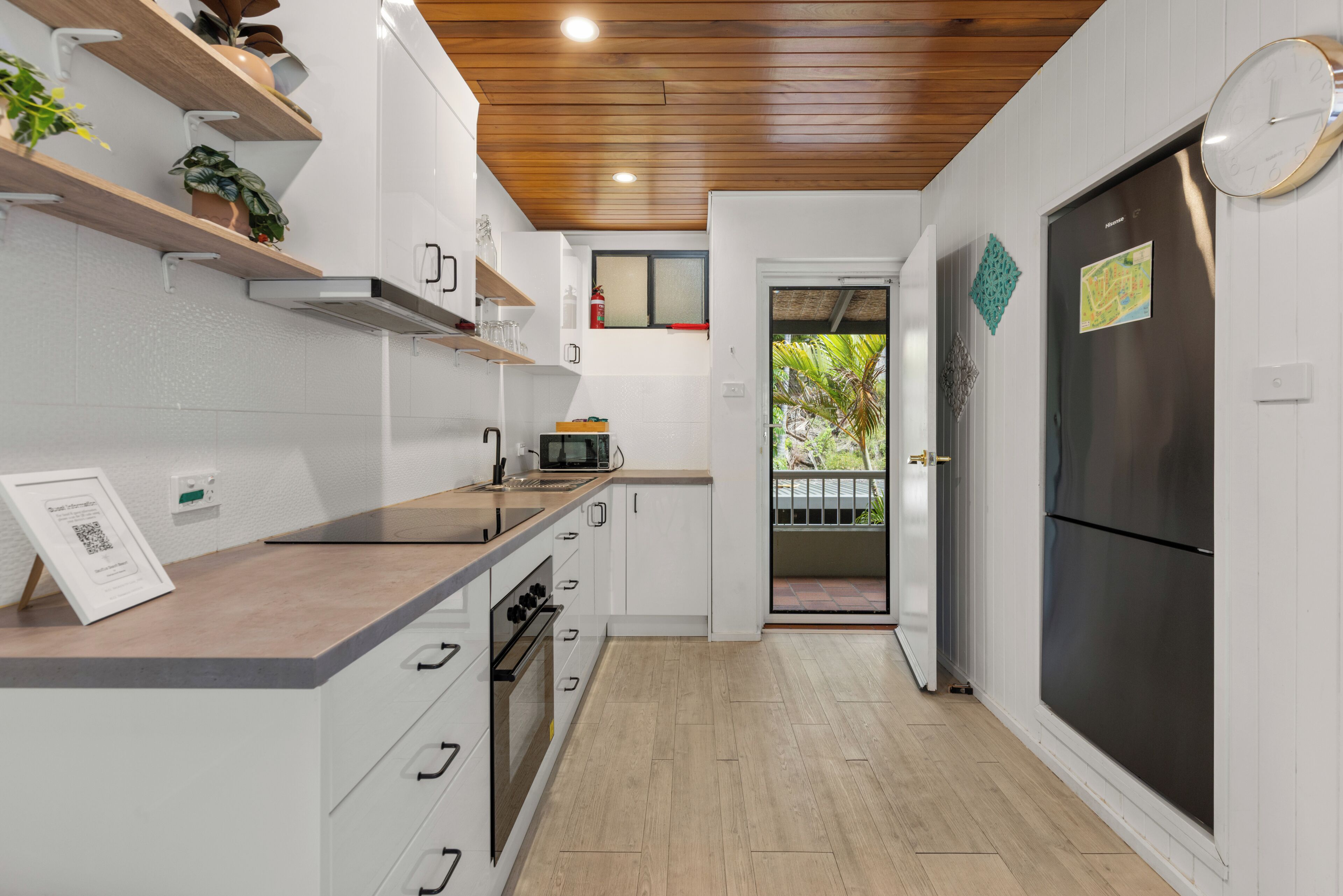 A modern kitchen with white cabinets, a wooden countertop, and a stainless steel refrigerator.