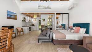 Un intérieur moderne comprenant un canapé, un lit, un téléviseur et un coin cuisine.