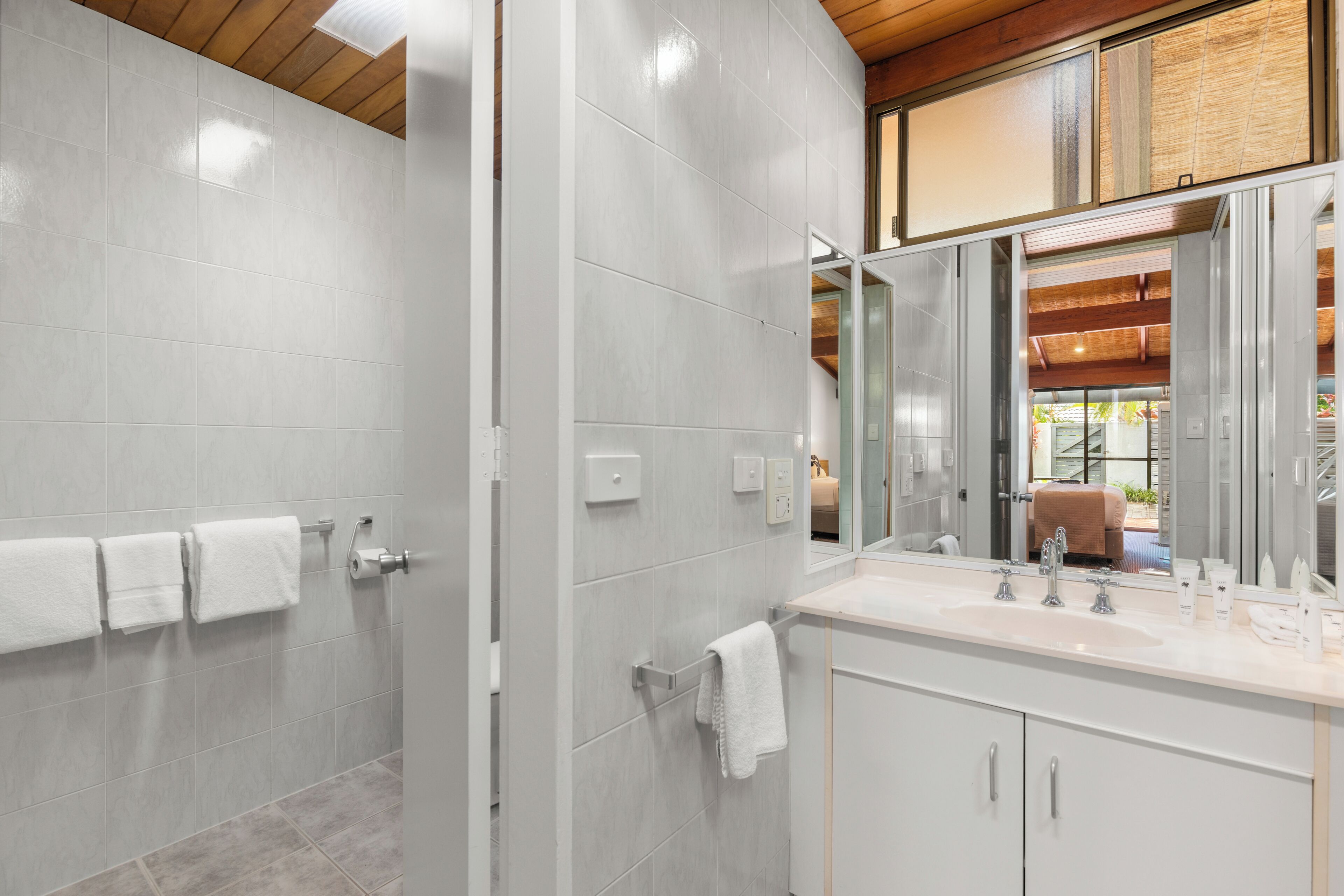 Een moderne badkamer met een douche, een wastafel en een spiegel.