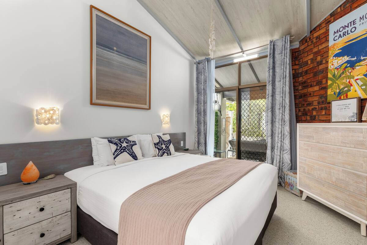 Ein Schlafzimmer mit Bett, Nachttisch, Wandbild und Kommode.
