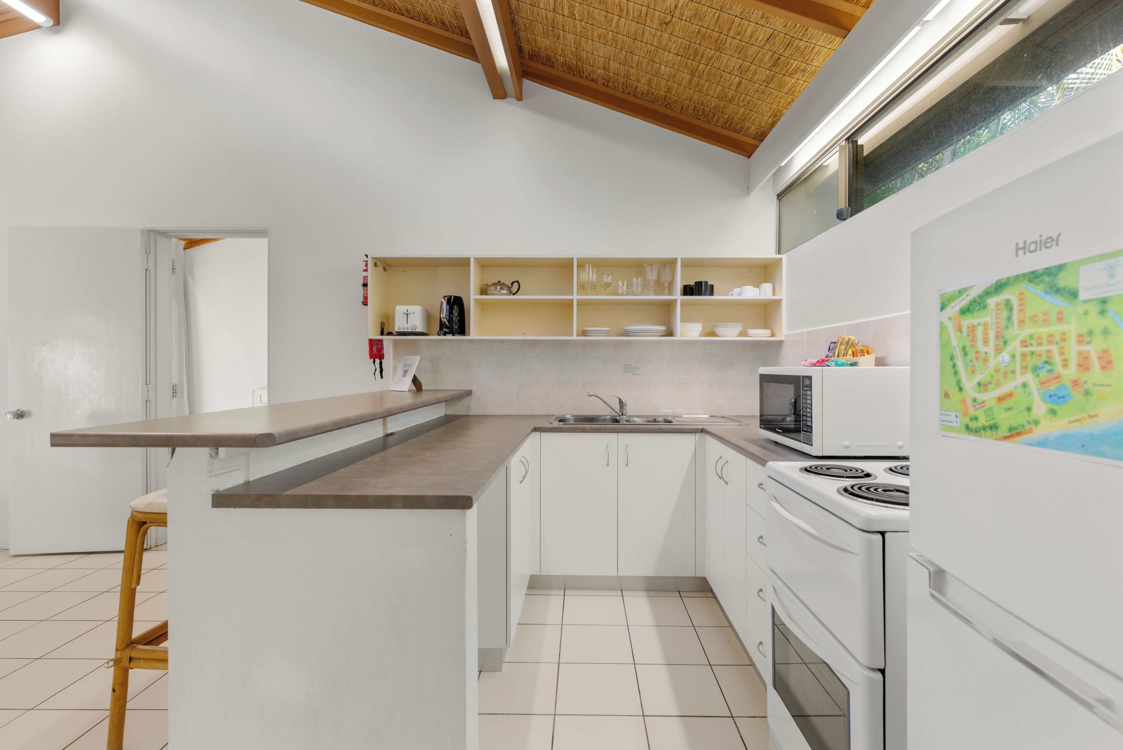 Een moderne keuken met witte kasten, een magnetron, fornuis en een kaart aan de muur.