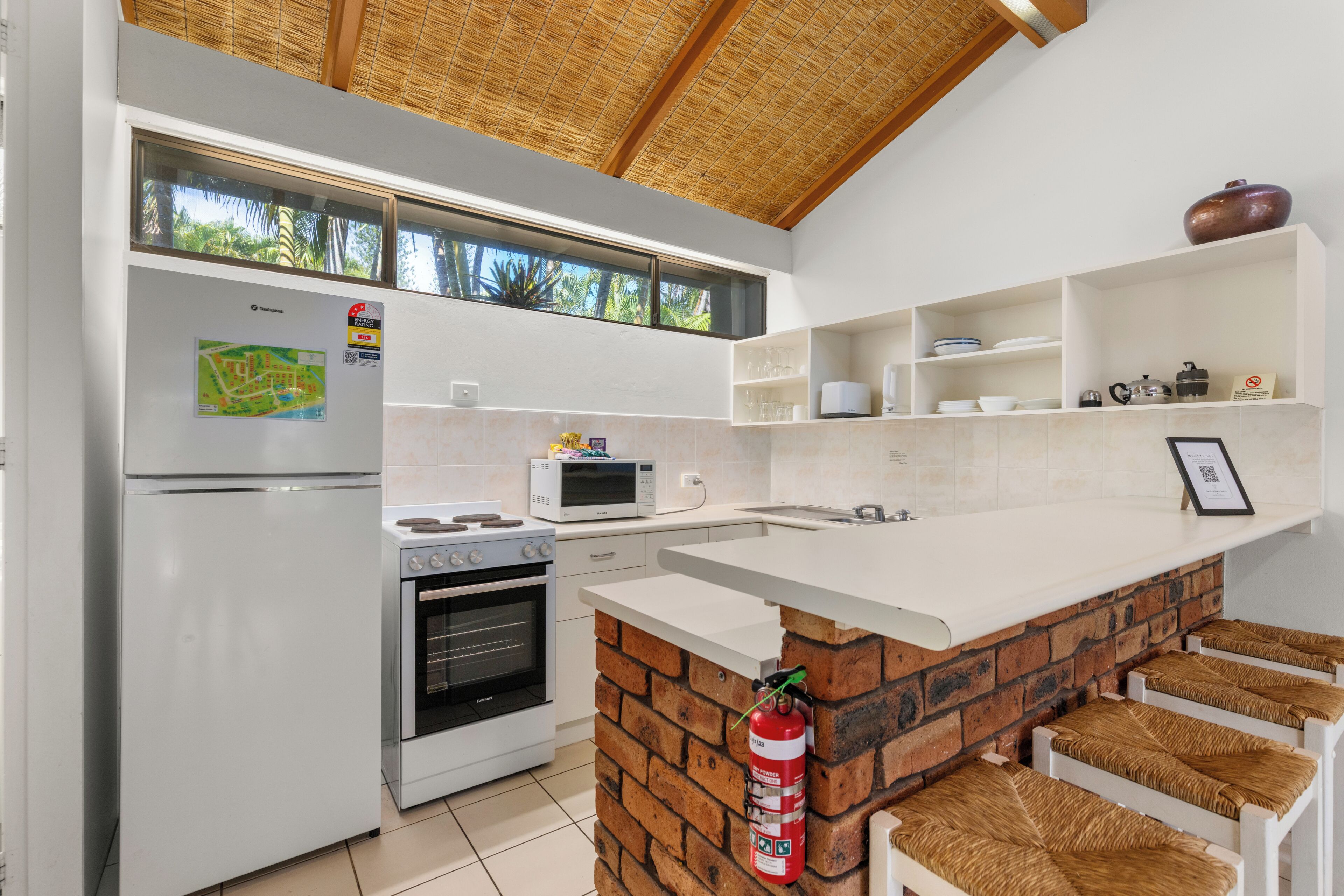 A kitchen with a refrigerator, microwave, oven, and a brick accent wall.
