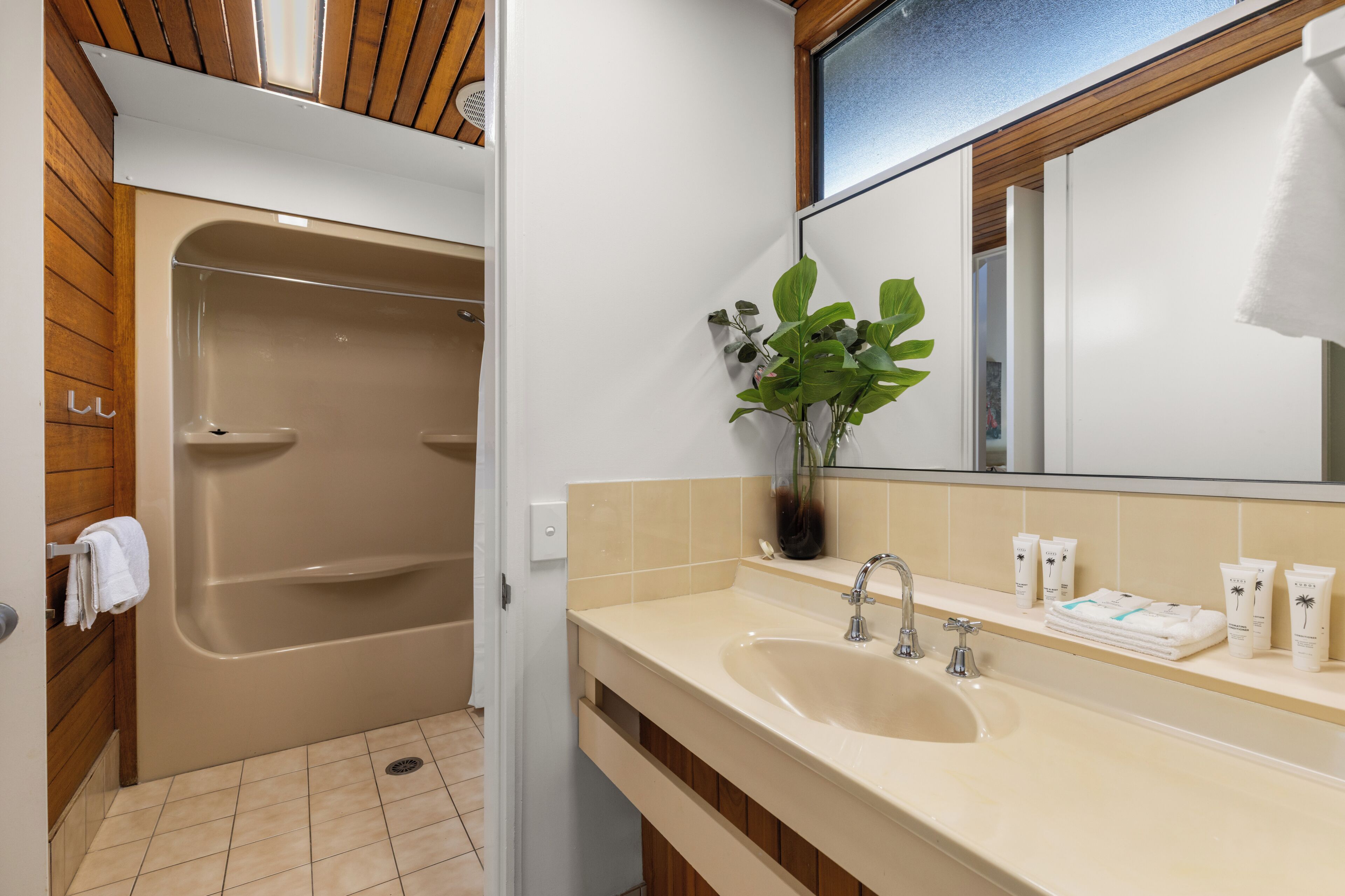 A bathroom with a bathtub, a sink, a mirror, and toiletries.