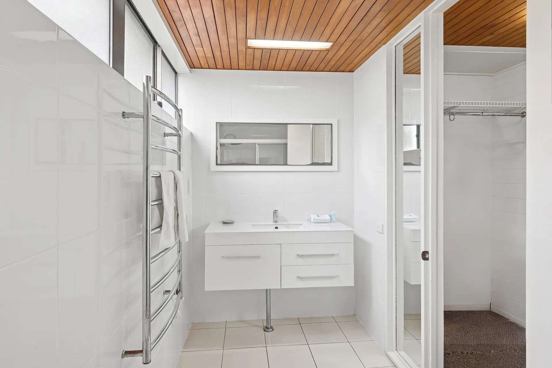Un baño moderno con tocador blanco, espejo y zona de ducha.