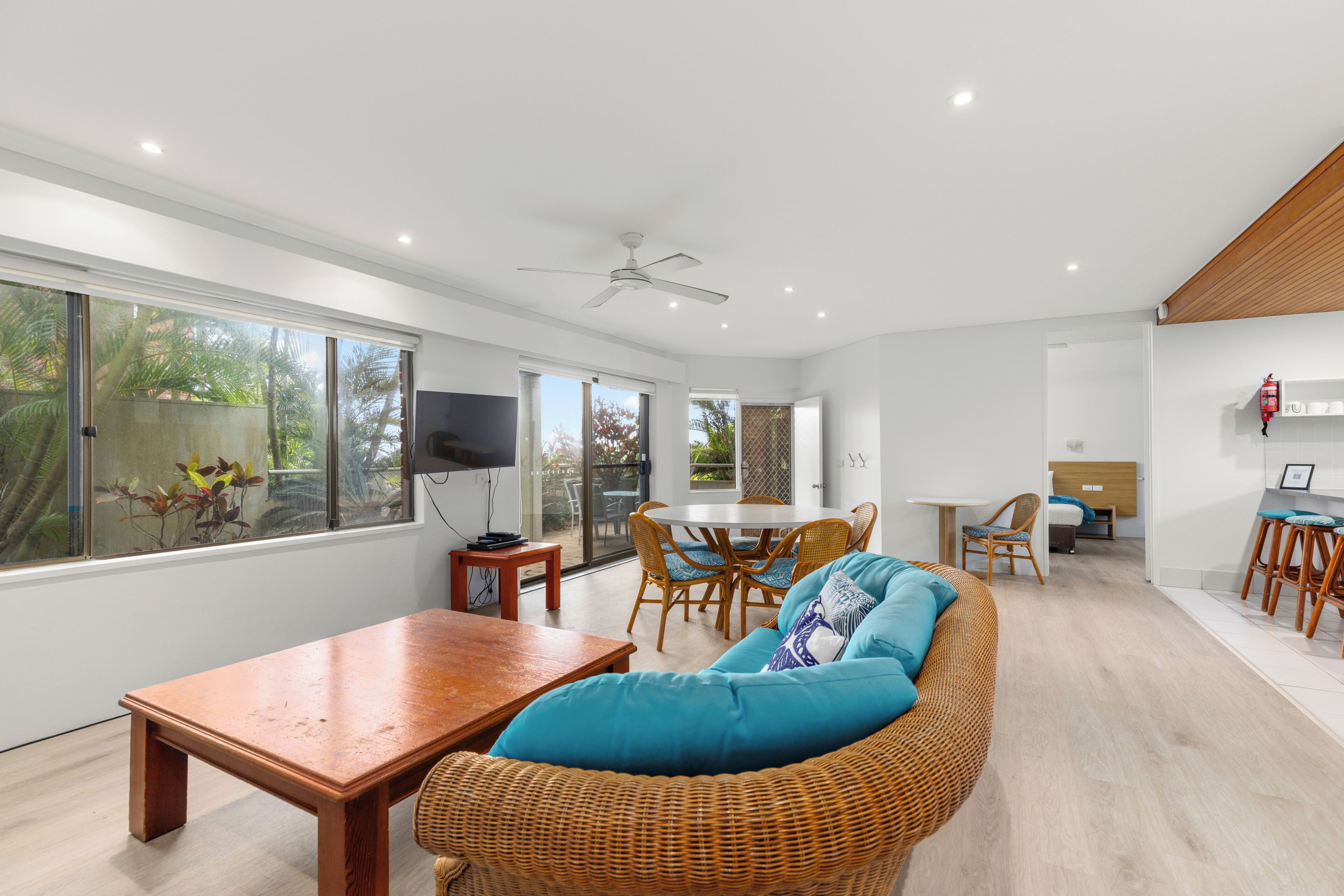 A modern interior with a dining area, a sofa with cushions, a wooden table, and a ceiling fan.