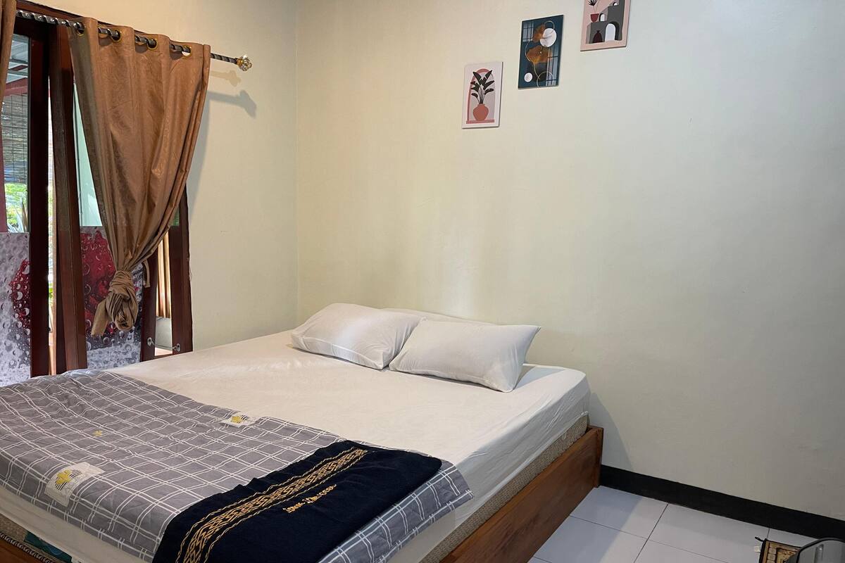 A bedroom with a bed, white pillows, a patterned bedspread, and a dark blue throw.