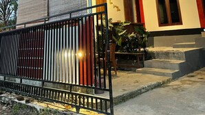 A building with a covered entrance, a metal roof, and a gated area with plants. - Rara Guest House Raja Ampat (Waisai)
