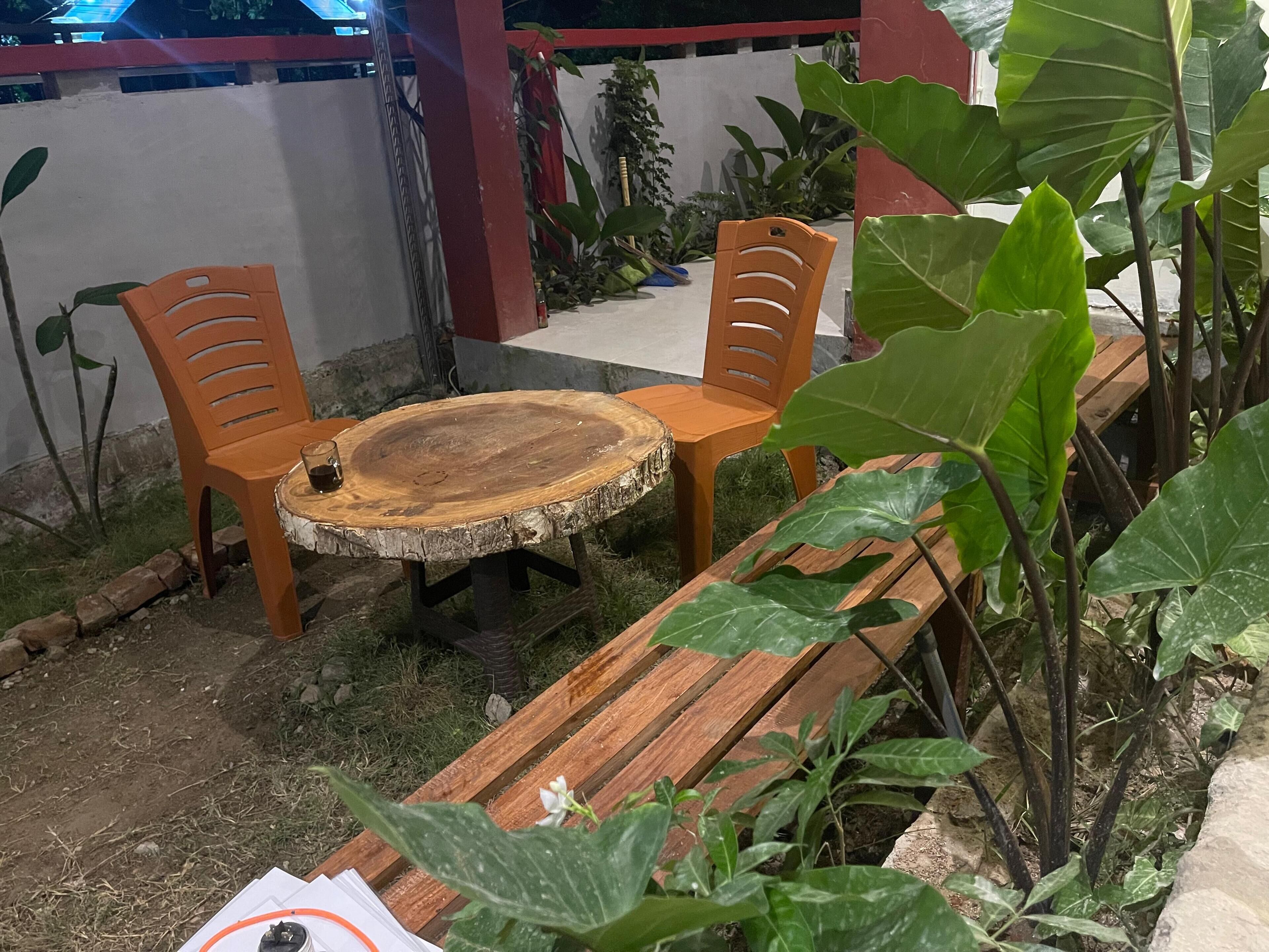 A wooden bench with a round table in the center, surrounded by chairs.