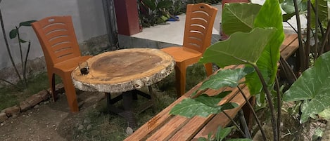 A wooden bench with a round table in the center, surrounded by chairs.