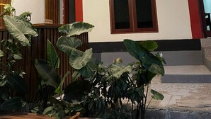 A reception area with a wooden reception desk, a large window, and potted plants. - Rara Guest House Raja Ampat (Waisai)