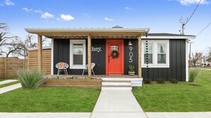 A house with a red door, a porch with two chairs, and a mailbox.