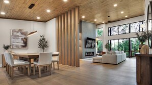 Un vaste espace de vie doté d’un plancher en bois, d’une table à manger avec des chaises, d’un canapé et d’un téléviseur fixé au mur.