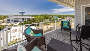 A balcony with wicker furniture, a view of a water tower, and a parking lot.