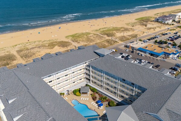 Vista aérea de un hotel con piscina, acceso a la playa y estacionamiento.