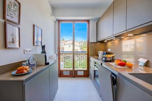 Une petite cuisine donnant sur l’extérieur, avec une machine à café et une assiette de croissants.
