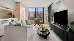 A modern apartment with a kitchen, dining area, and living room. - Luxury Sky High Apartment with Pool Gym & Parking (South Melbourne)
