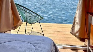 A tent with a view of the sea, a chair, and a bed. - Floating Home in Reef Resort Unit 5 (Samal)