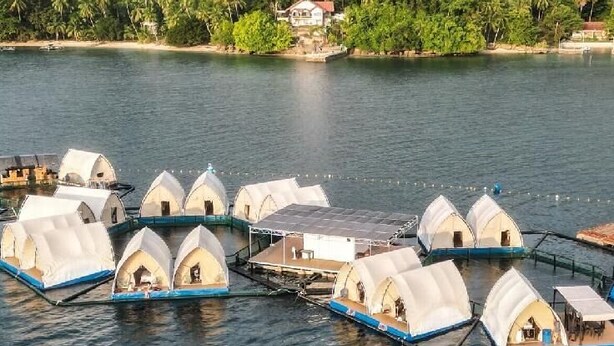 A series of dome-shaped accommodations on water, connected by walkways, with a forested hill in the background. - Floating Home in Reef Resort Unit 5 (Samal)