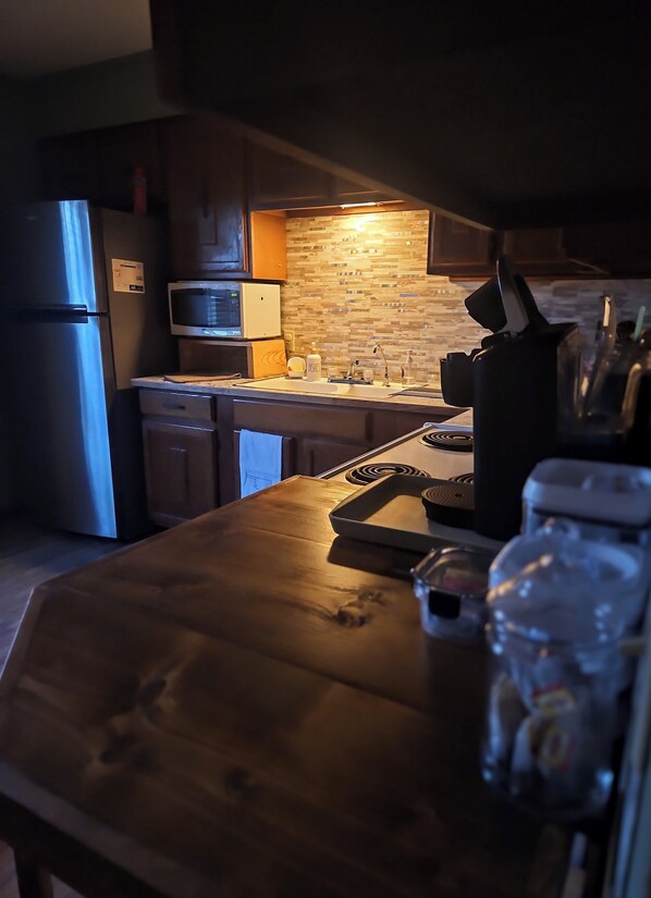 Una cocina con refrigerador, microondas y salpicadero de azulejos.