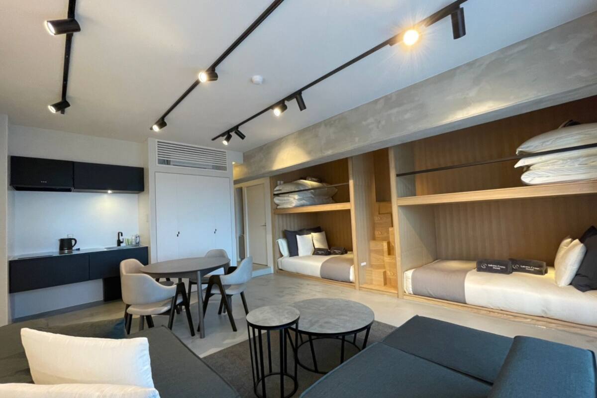 Una habitación de hotel moderna con comedor, sofá y cama con estantes de almacenamiento.