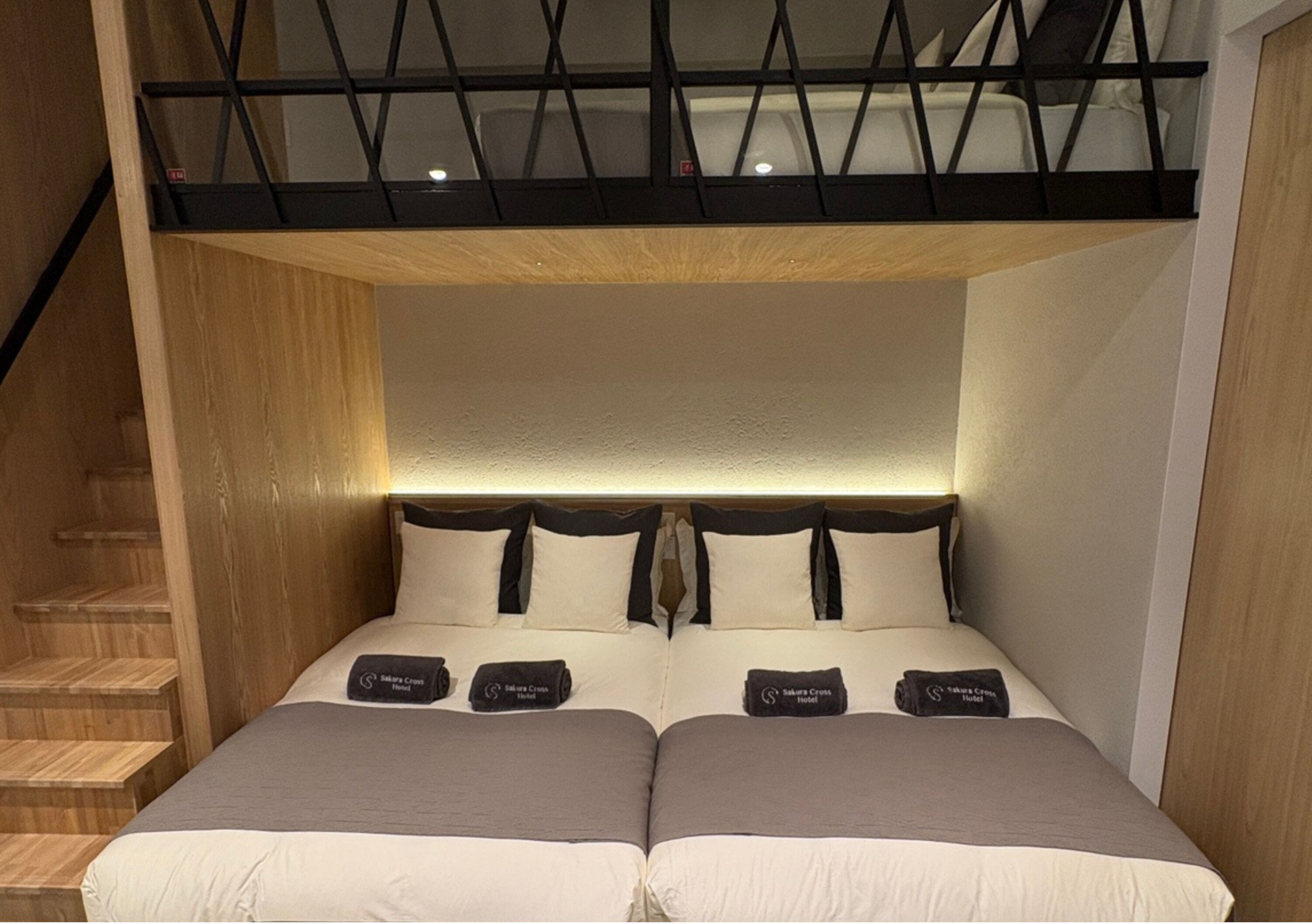 Un letto matrimoniale con testiera, due cuscini e una coperta. Si vede una scala in legno sulla sinistra.