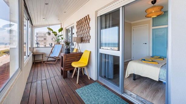 Ein Balkon mit Holzboden, einem Tisch, zwei Stühlen und Meerblick.