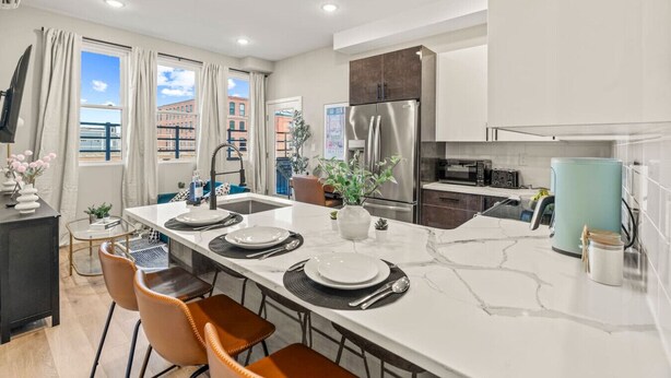 A modern kitchen with a central island, stainless steel appliances, and a view of the city. - Luxury 1BR|1BA in the Heart of Fishtown (Philadelphia)