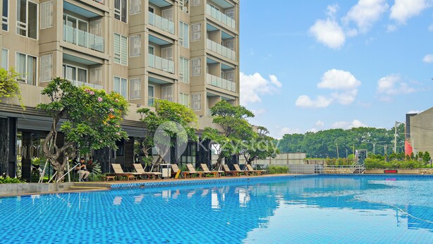 Una piscina con sillas de descanso y un edificio con balcones al fondo.