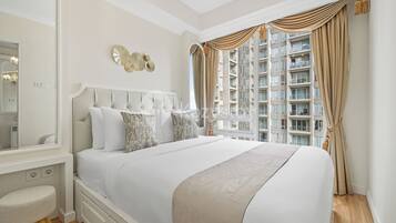Un dormitorio con una cama grande, una tocador con espejo y vistas a un edificio de gran altura.