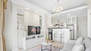 Una sala moderna con televisor, sofá y una mesita con un florero.