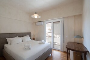 A bedroom with a bed, a nightstand, a lamp, and a sliding glass door to a balcony.