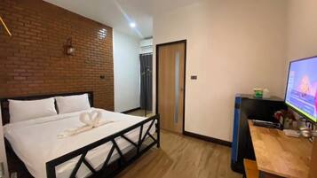 Habitación de hotel con cama, escritorio, computadora y zona de ducha.