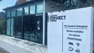 Una cafetería llamada 'Connect Coffee' con un letrero que anuncia disponibilidad de habitaciones y un número de contacto.