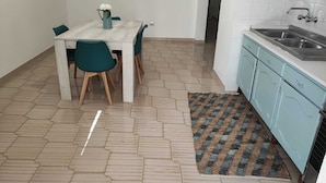 Eine kleine Küche mit Spüle, einem Esstisch mit Stühlen und einem gemusterten Teppich.