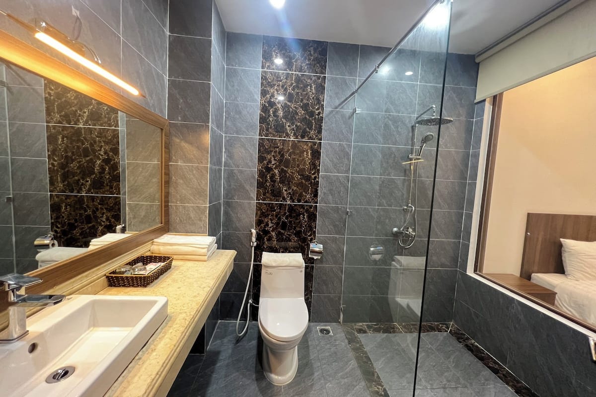 Een moderne badkamer met een grote spiegel, een wastafel, toilet en douche.