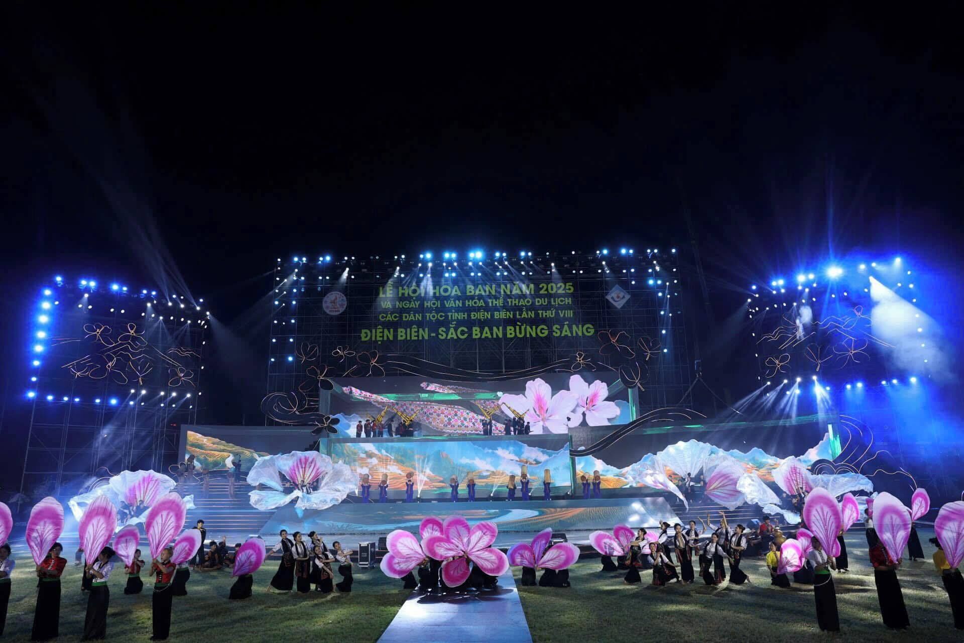 Um palco com artistas e uma tela grande exibindo texto em vietnamita.