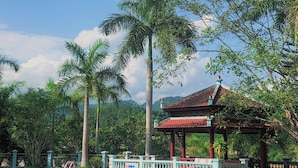A swimming pool with a pink flamingo float, surrounded by palm trees and a gazebo. - Him Lam Eco Resort (Dien Bien Phu)
