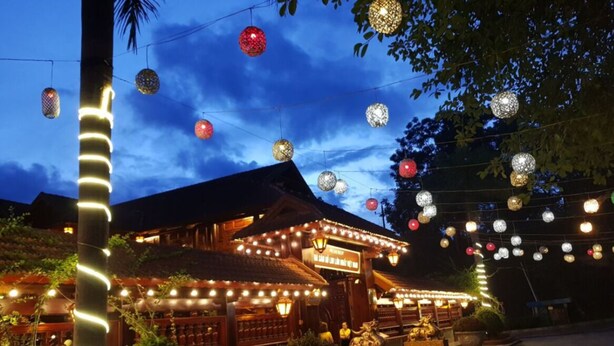 A traditional building with a thatched roof, illuminated by string lights and lanterns. - Him Lam Eco Resort (Dien Bien Phu)