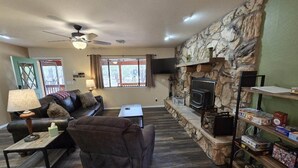 Una sala de estar con chimenea de piedra, sofá de cuero y televisor.