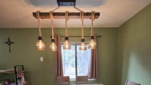 Un comedor con una mesa de madera, seis sillas y una lámpara en el techo.