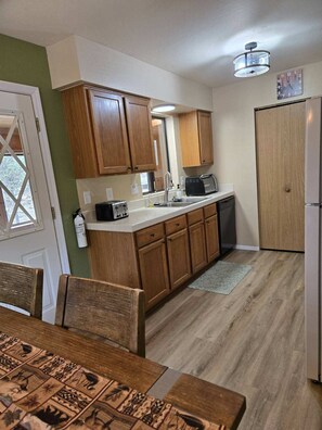 Una cocina compacta con armarios de madera, un tostador empotrado y un refrigerador.