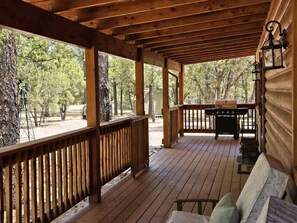 A covered porch with wooden railings, a grill, and a bench. - Nestled in the trees, family cabin room for 8, open for fall break & hunters! (Nutrioso)
