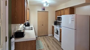 Una cocina compacta con armarios de madera, un refrigerador blanco y un microondas.