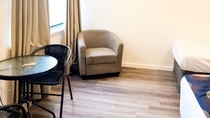 Une pièce avec un lit, une chaise, une table et des rideaux.