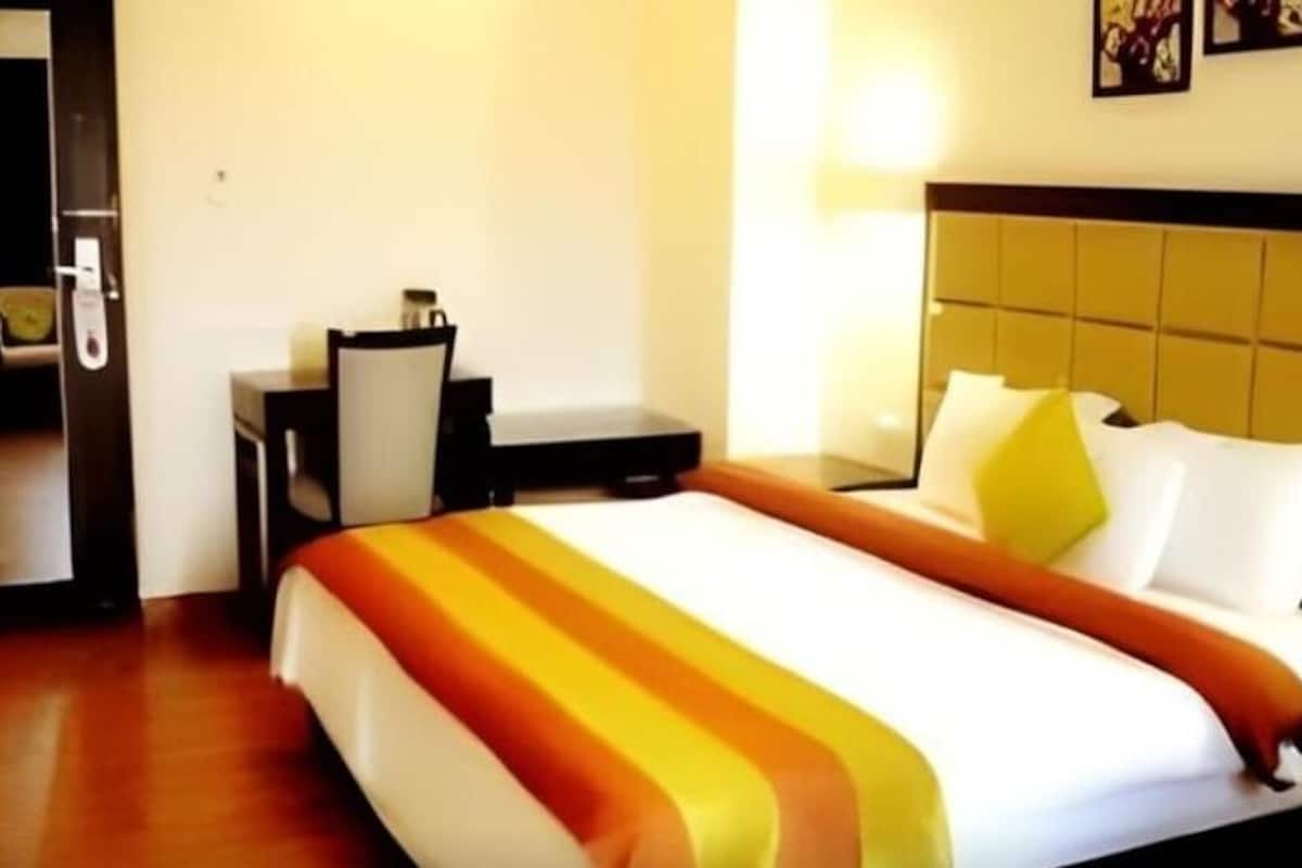 A hotel room with a bed, a desk, and a chair.