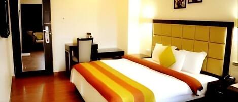 A hotel room with a bed, a desk, and a chair.