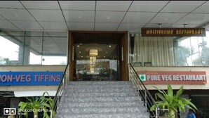 L’entrée d’un immeuble donne sur un escalier menant à deux restaurants : le premier s’appelle « MULTICUISINE RESTAURANT » et le second, « PURE VEG RESTAURANT ».